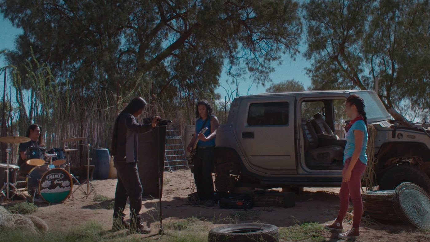 Una banda toca en un patio de tierra junto a una camioneta